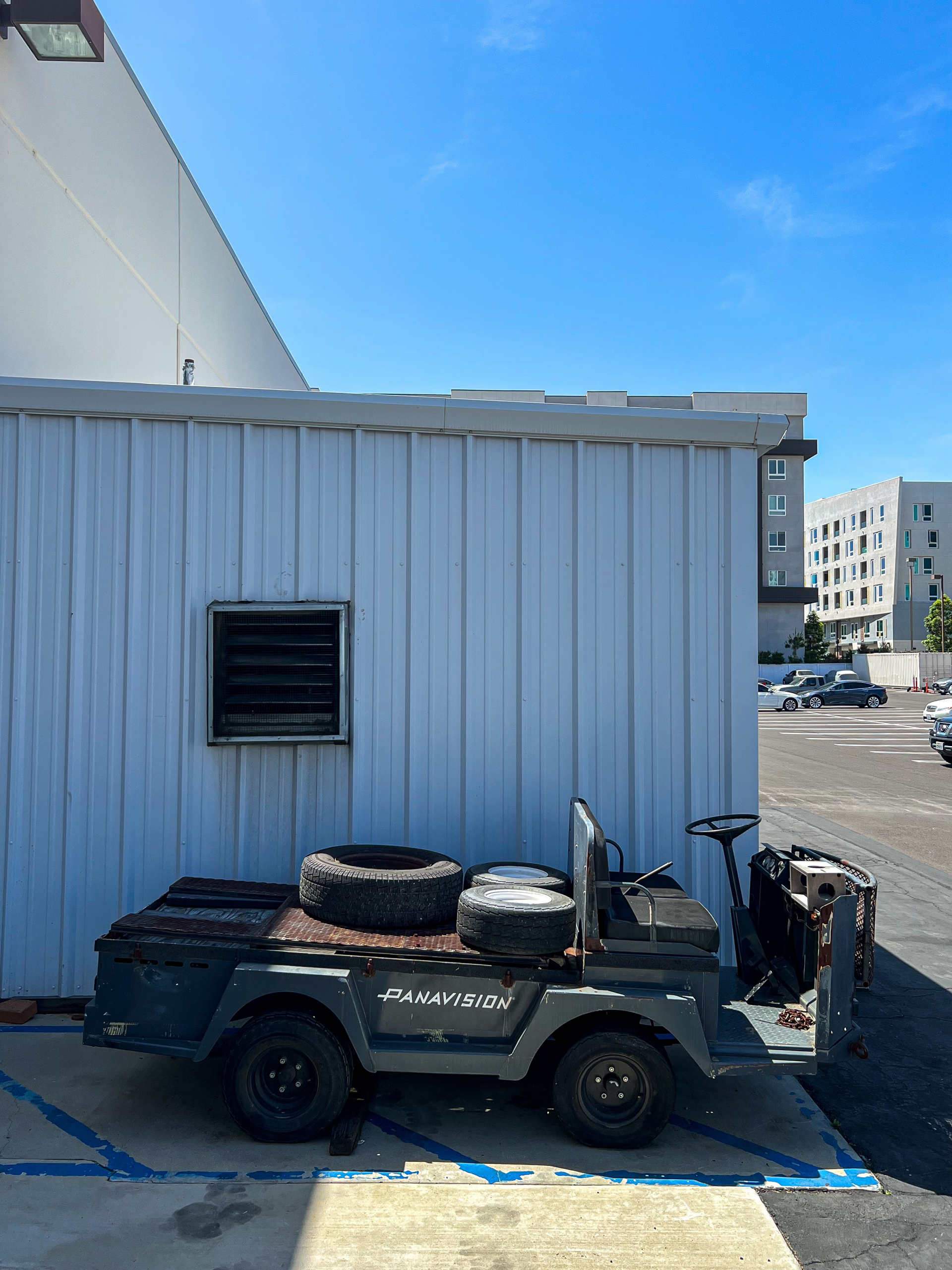 Small Utility Vehicle is parked alongside a shed in a parking lot